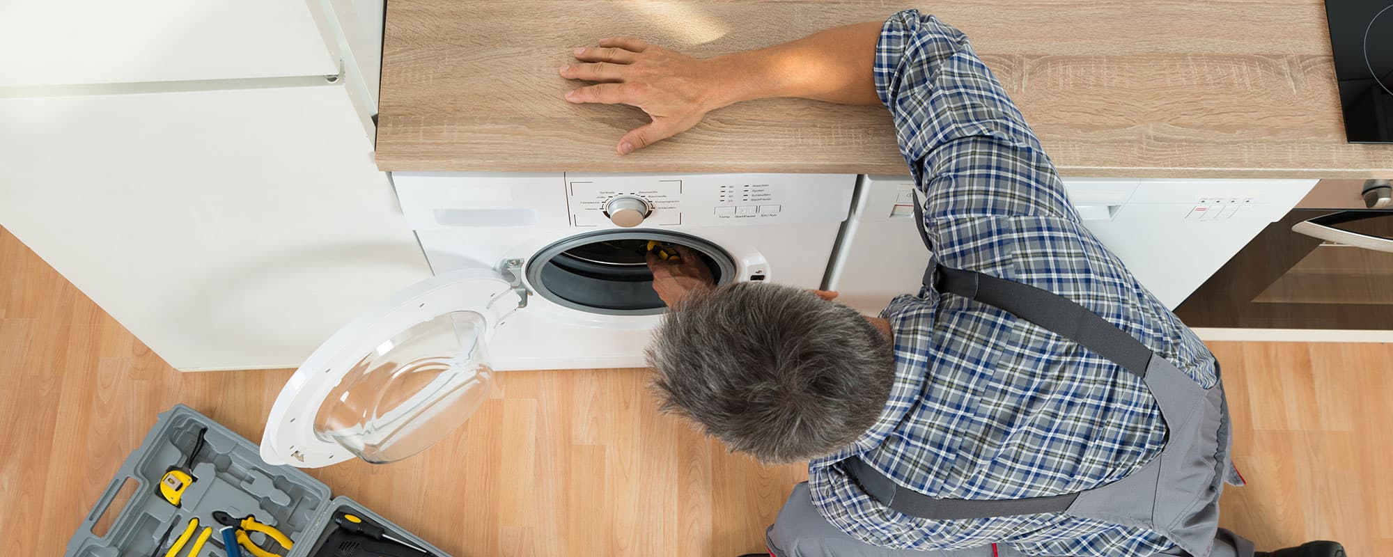 High angle view of handyman checking washing machine at home